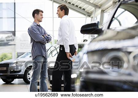 Stock Photo - A young man talking to a car salesman. Fotosearch