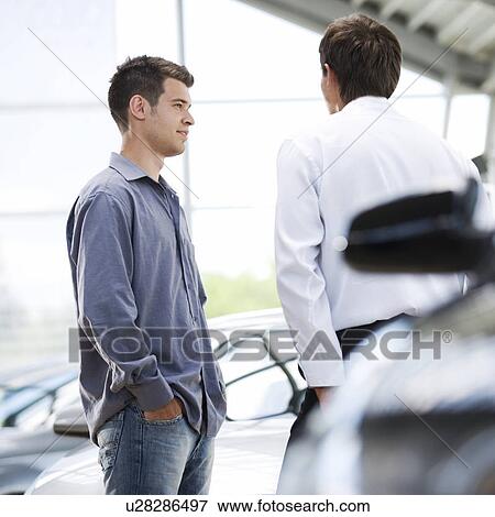 Stock Photo - A young man talking to a car salesman. Fotosearch