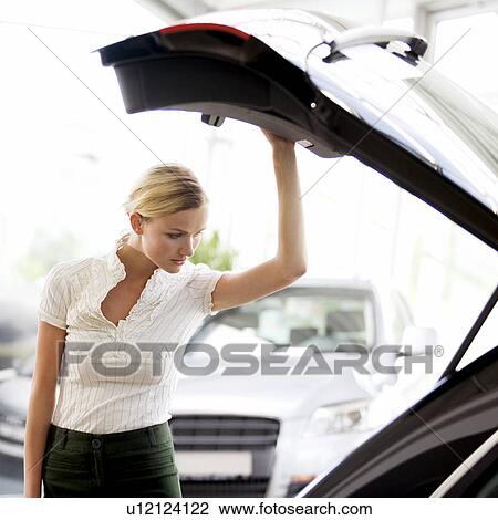 Stock Image - A young woman admiring a new car. Fotosearch