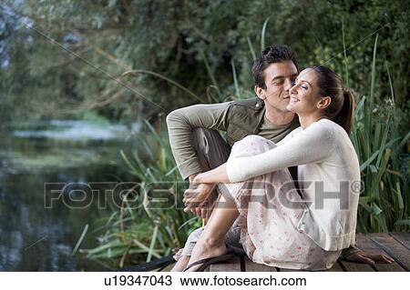 Young couple sitting by a river View Large Photo Image Stock Image - Young couple sitting by a river. Fotosearch