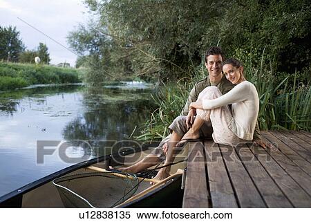 Stock Photography - Young couple sitting by a river. Fotosearch
