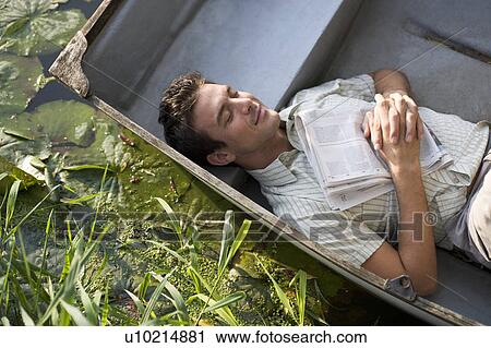Stock Image - Young man asleep in a boat. Fotosearch
