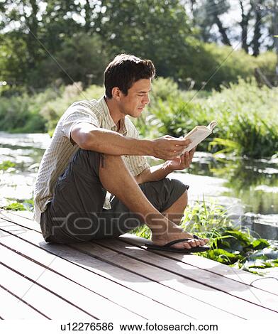 Young man reading a book View Large Photo Image Stock Photograph - Young man reading a book. Fotosearch