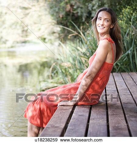 Young woman sitting by a river View Large Photo Image Stock Photo - Young woman sitting by a river. Fotosearch