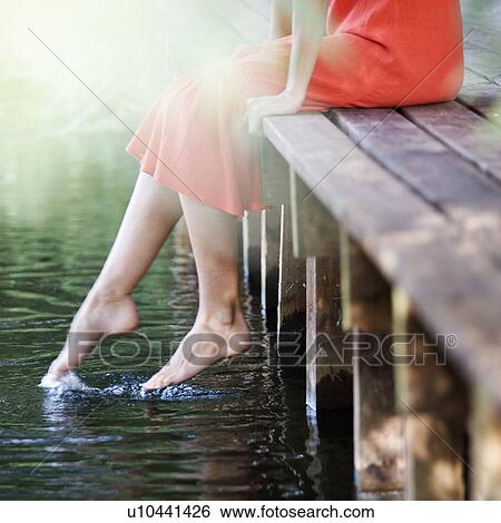Stock Photograph - Young woman sitting by a river. Fotosearch