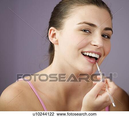 Stock Image - A teenage girl applying lip gloss. Fotosearch