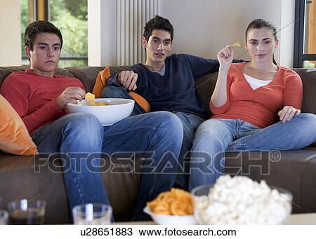 Three teenage friends watching television View Large Photo Image Stock Image - Three teenage friends watching television. Fotosearch