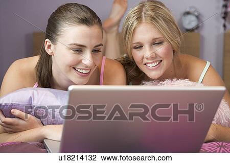 Two teenage girls using a laptop View Large Photo Image Stock Image - Two teenage girls using a laptop. Fotosearch