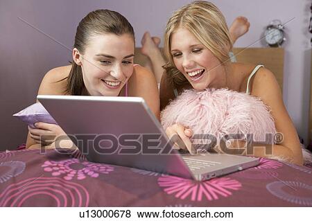 Two teenage girls using a laptop View Large Photo Image Stock Photo - Two teenage girls using a laptop. Fotosearch
