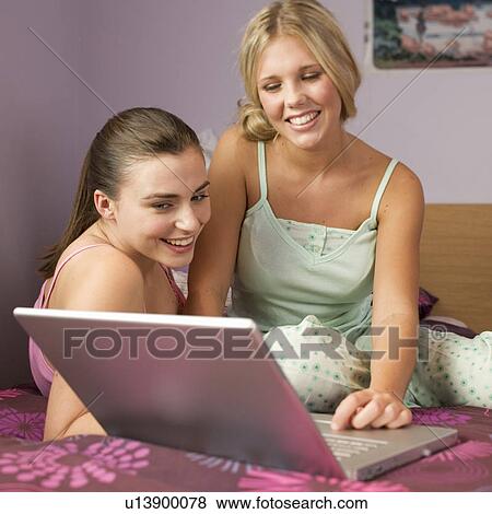 Two teenage girls using a laptop View Large Photo Image Stock Photo - Two teenage girls using a laptop. Fotosearch