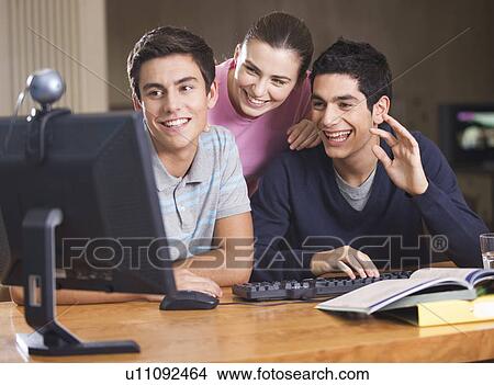Picture - Three teenage friends using a computer. Fotosearch