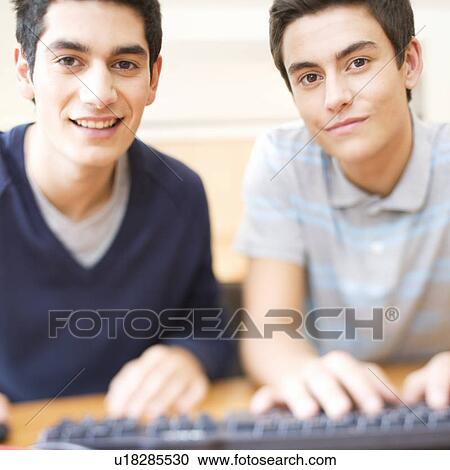 Stock Image - Two teenage boys using a computer. Fotosearch