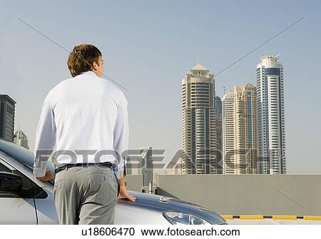 A businessman standing by a car View Large Photo Image Stock Image - A businessman standing by a car. Fotosearch