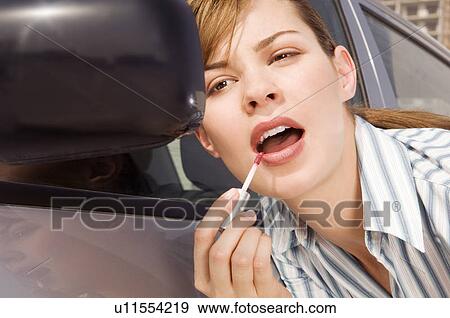Stock Photo - A businesswoman applying lip gloss. Fotosearch