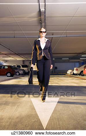 Stock Image - A businesswoman walking in a car park. Fotosearch