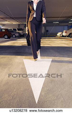 Stock Photo - A businesswoman walking in a car park. Fotosearch