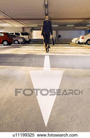 Stock Photography - A businesswoman walking in a car park. Fotosearch