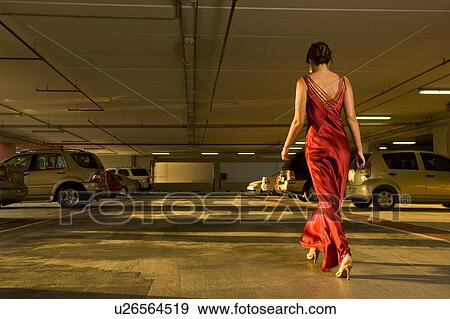 Stock Photo - A woman in evening dress walking in a car park. Fotosearch