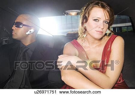 A woman sitting in the back of a car with her security guard View Large Photo Image Stock Image - A woman sitting in the back of a car with her security guard. Fotosearch
