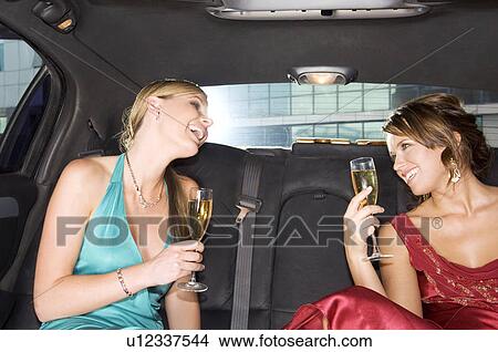 Two women drinking champagne in the back of a car View Large Photo Image Picture - Two women drinking champagne in the back of a car. Fotosearch
