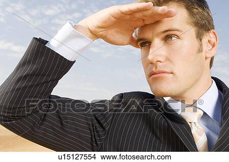 A man in a suit shielding his eyes from the sun View Large Photo Image Picture - A man in a suit shielding his eyes from the sun. Fotosearch