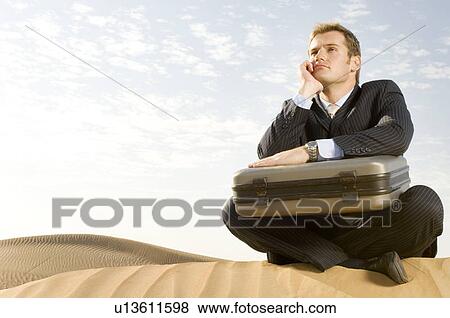 A man with a suitcase sitting in a desert View Large Photo Image Stock Photo - A man with a suitcase sitting in a desert. Fotosearch