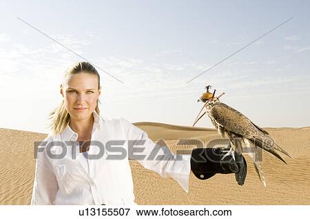 A woman standing in the desert with a hawk View Large Photo Image Stock Photo - A woman standing in the desert with a hawk. Fotosearch