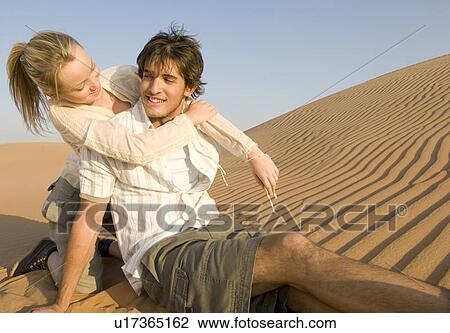 Stock Image - A young couple sitting in the desert. Fotosearch