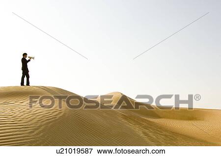 Stock Photo - A young man standing in the desert with a loud hailer. Fotosearch