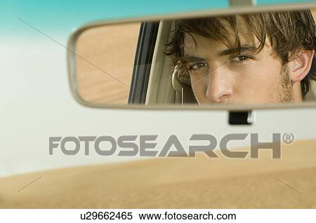 A young man's reflection in a rear view mirror View Large Photo Image Stock Photography - A young man's reflection in a rear view mirror. Fotosearch