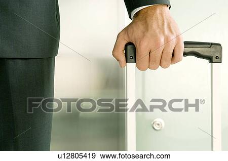 Stock Photo - A businessman holding a suitcase. Fotosearch