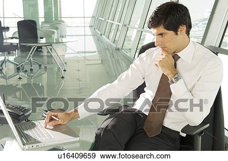 Stock Photo - A businessman sitting at his desk. Fotosearch