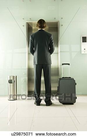 A businessman with a suitcase waiting for the lift View Large Photo Image Stock Image - A businessman with a suitcase waiting for the lift. Fotosearch
