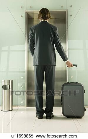 A businessman with a suitcase waiting for the lift View Large Photo Image Stock Photography - A businessman with a suitcase waiting for the lift. Fotosearch