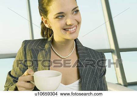 Picture - A businesswoman drinking coffee at an airport. Fotosearch