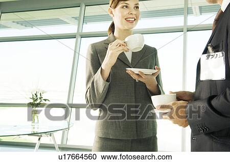 Stock Image - A businesswoman having a cup of coffee with a visiting colleague. Fotosearch