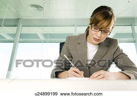 A businesswoman sitting at a table View Large Photo Image Stock Photo - A businesswoman sitting at a table. Fotosearch
