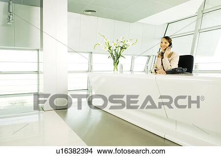 A receptionist talking on the telephone View Large Photo Image Picture - A receptionist talking on the telephone. Fotosearch