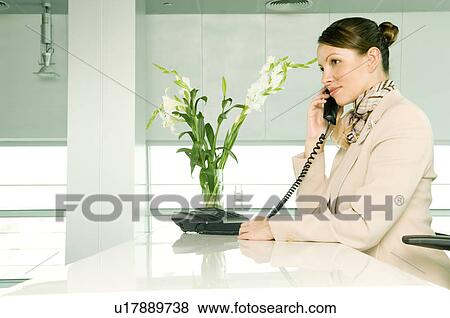 Stock Photo - A receptionist talking on the telephone. Fotosearch