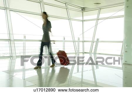 A woman walking through an airport View Large Photo Image Stock Image - A woman walking through an airport. Fotosearch