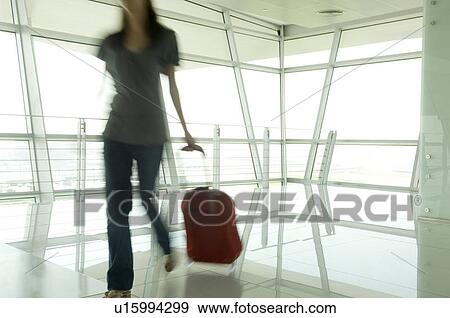 A woman walking through an airport View Large Photo Image Stock Photo - A woman walking through an airport. Fotosearch