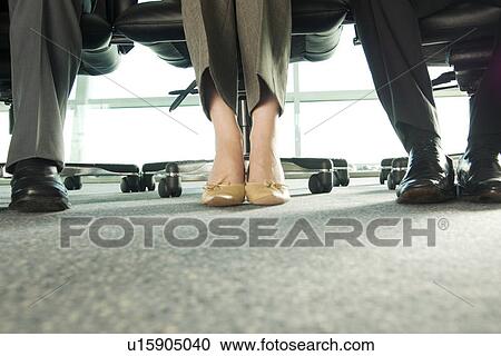 Stock Image - Feet under a desk. Fotosearch