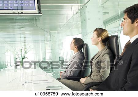 Stock Photo - Three business colleagues watching a presentation. Fotosearch