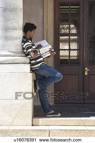 Stock Image - A student carrying a pile of books. Fotosearch