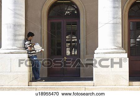 Stock Image - A student carrying a pile of books. Fotosearch