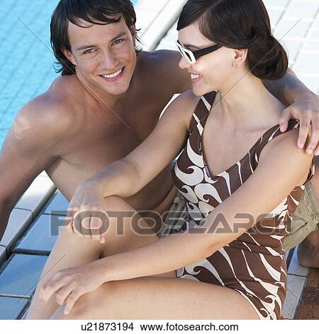 A young couple sitting by a swimming pool View Large Photo Image Picture - A young couple sitting by a swimming pool. Fotosearch