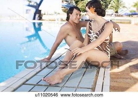 A young couple sitting by a swimming pool View Large Photo Image Stock Photograph - A young couple sitting by a swimming pool. Fotosearch