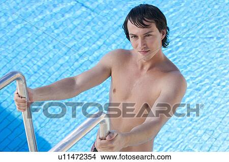 A young man climbing into a swimming pool View Large Photo Image Picture - A young man climbing into a swimming pool. Fotosearch