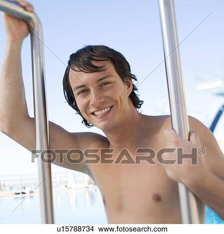 A young man climbing into a swimming pool View Large Photo Image Picture - A young man climbing into a swimming pool. Fotosearch