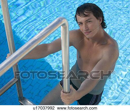 A young man climbing into a swimming pool View Large Photo Image Stock Image - A young man climbing into a swimming pool. Fotosearch